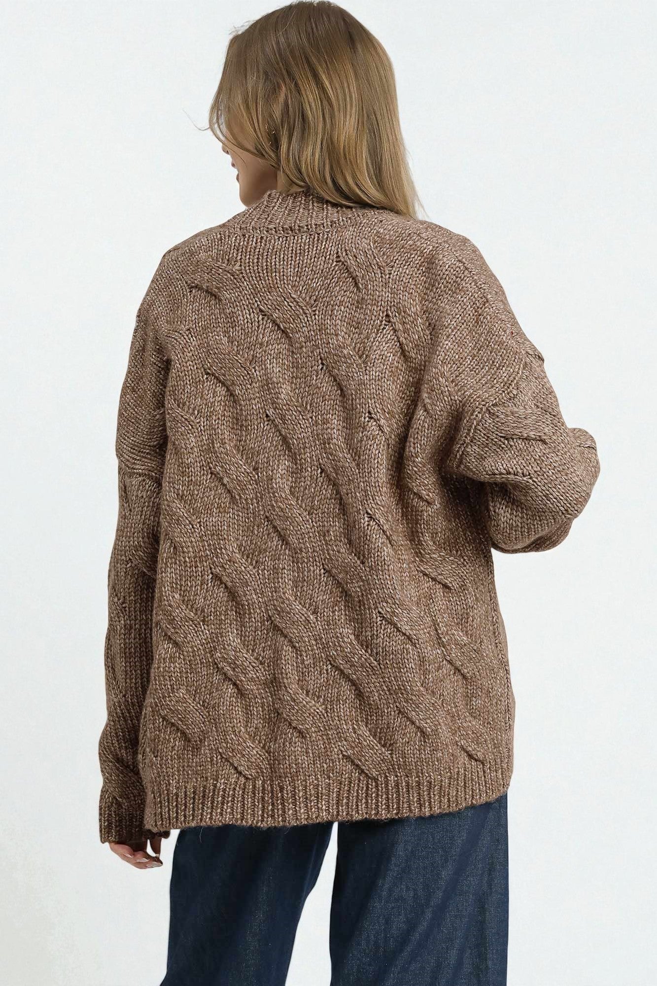 Person wearing a brown cable knit sweater on a white background