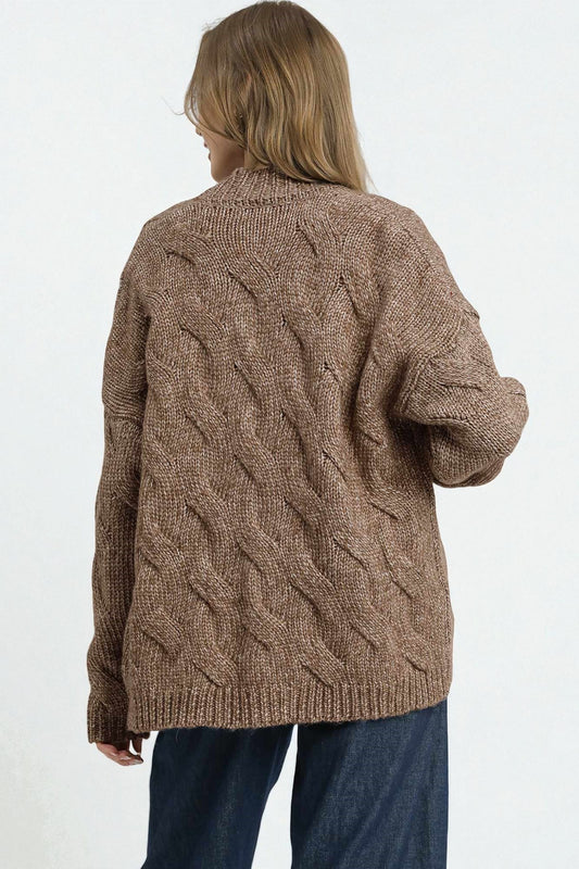 Person wearing a brown cable knit sweater on a white background