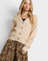 Woman wearing a beige cardigan and leopard print pants on a white background
