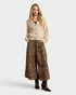 Woman wearing a beige cardigan and leopard print skirt on a white background