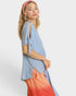 Woman wearing a light blue top with cut-out shoulders and an orange skirt on a white background