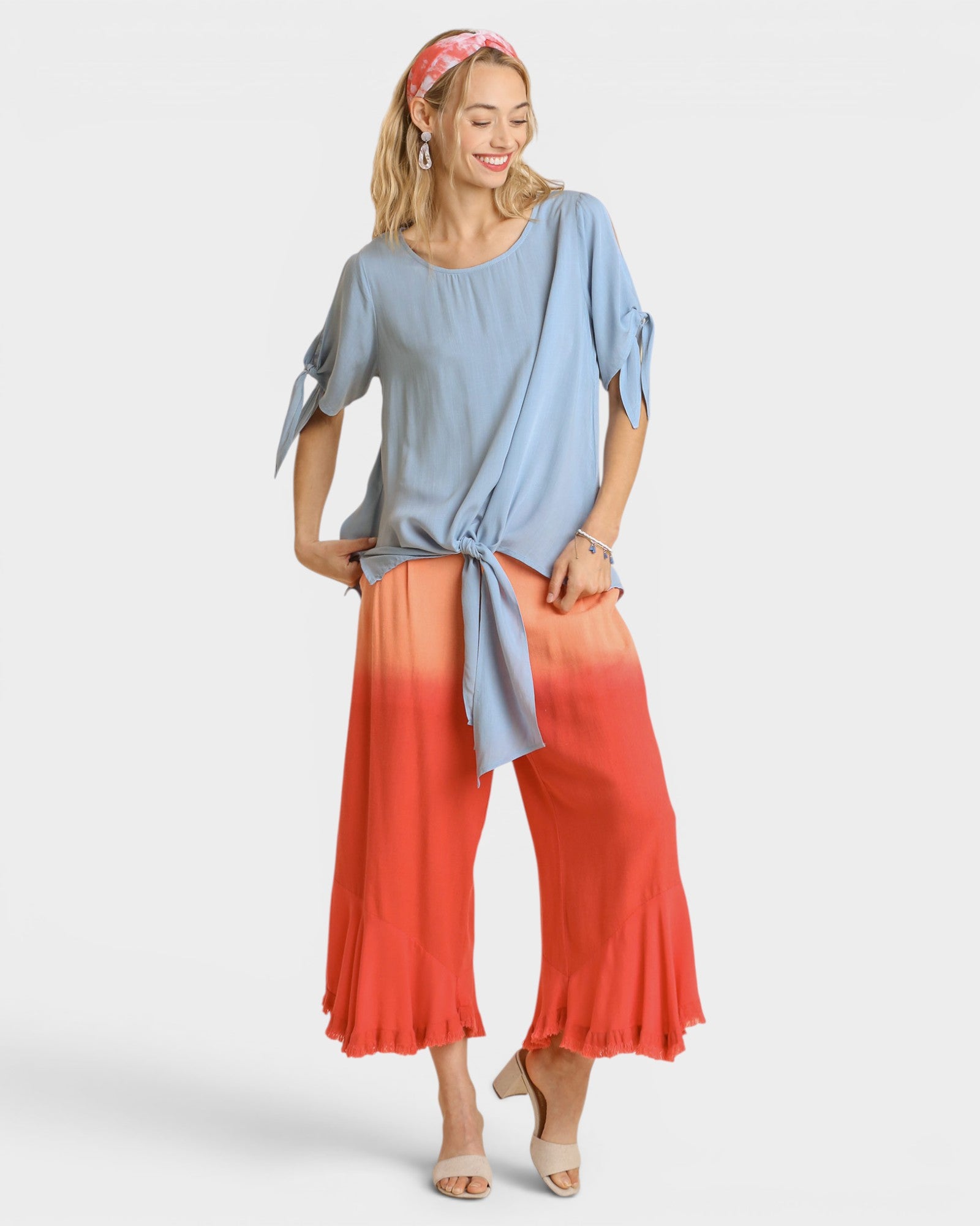 Woman wearing a blue top and red-orange pants on a white background