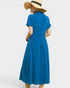 Woman wearing a blue dress and straw hat on a light gray background