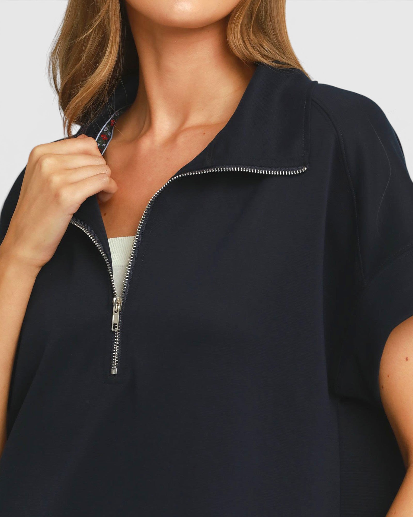 Woman wearing a navy blue zip-up top against a white background