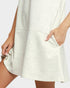 Close-up of a person wearing a white dress with a plain background