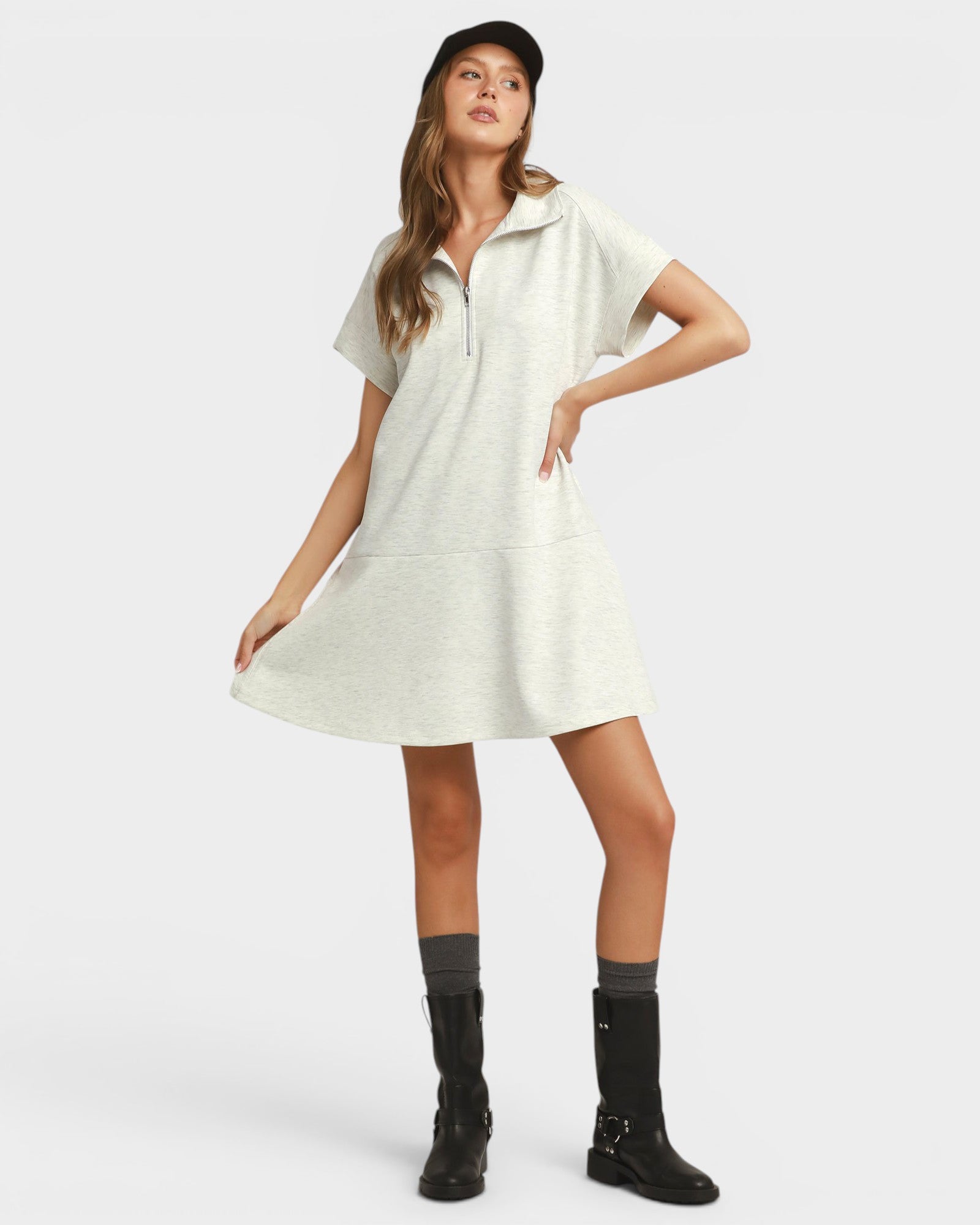 Woman wearing a white dress with black boots on a white background