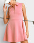 Woman wearing a pink dress holding a golf club on a light gray background