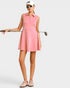 Woman in a pink golf dress holding a golf club on a white background