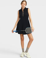 Woman in a navy dress holding a badminton racket on a white background