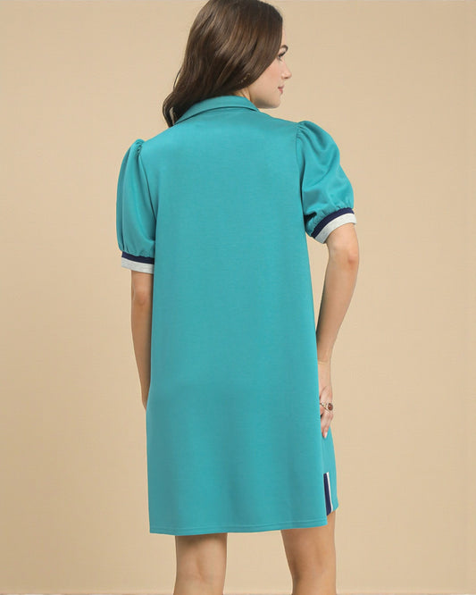 Woman wearing a teal dress with white trim on a beige background