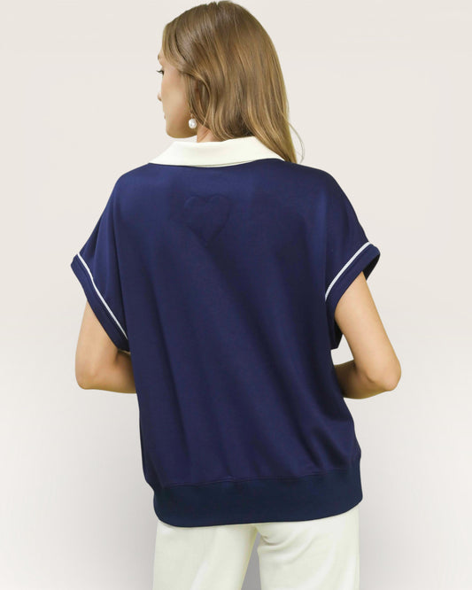 Woman wearing a navy blue sleeveless top with white trim on a plain background