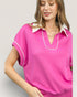 Woman wearing a pink polo shirt with white trim on a light gray background