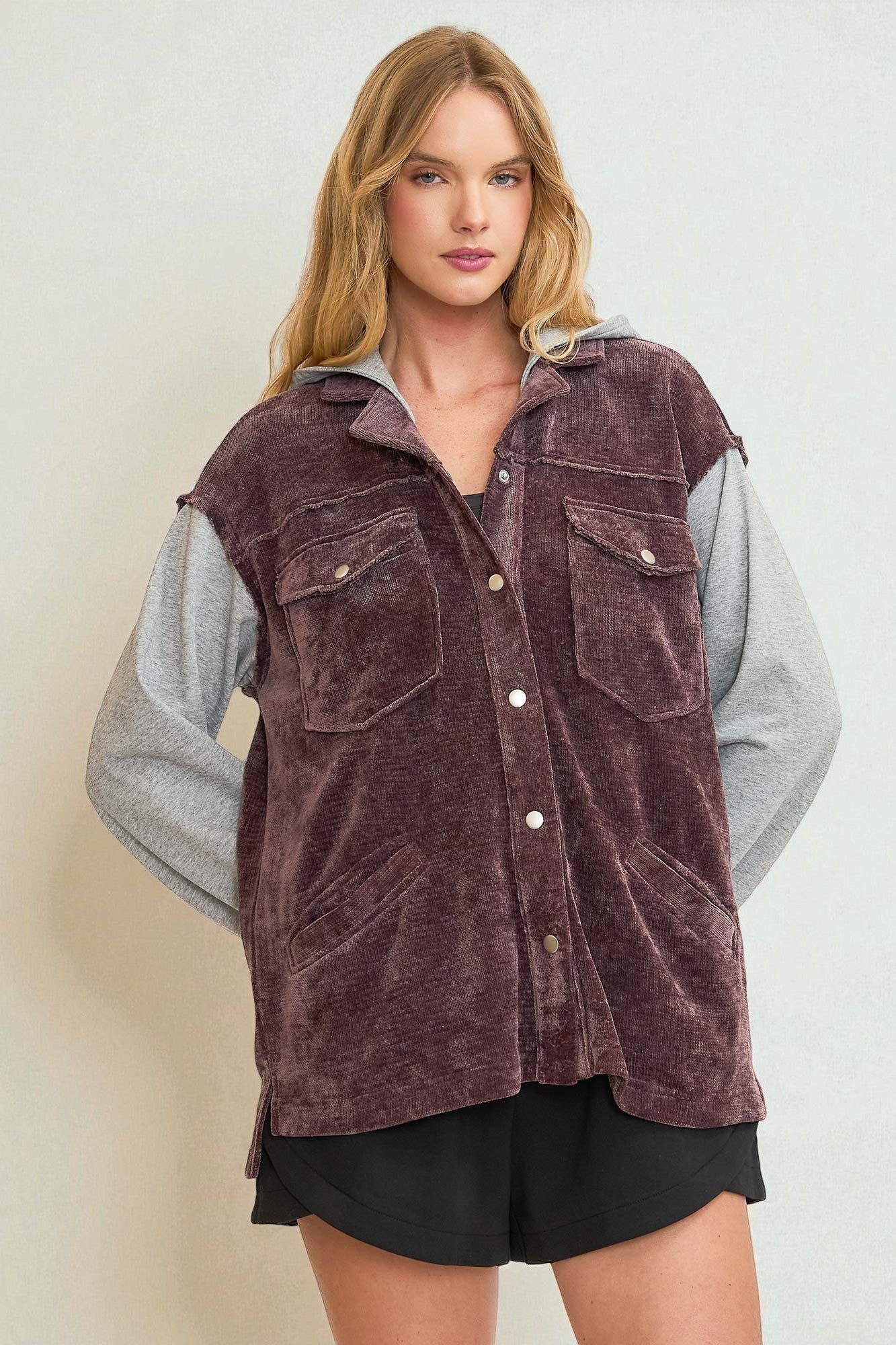 Woman wearing a brown corduroy vest over a gray shirt on a white background