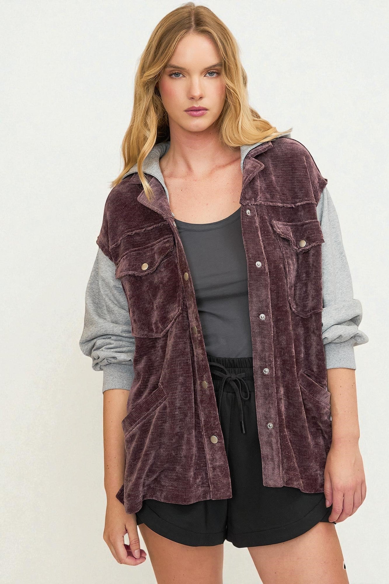 Woman wearing a purple corduroy vest over a gray shirt on a white background