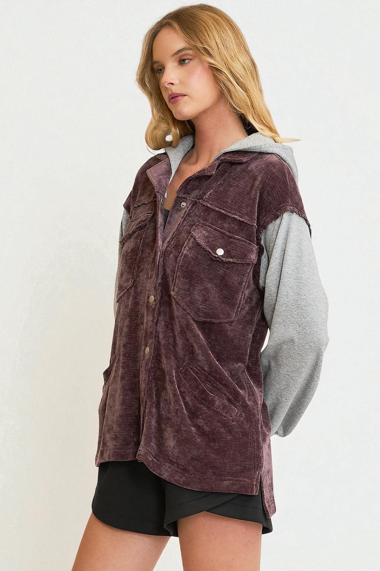 Woman wearing a brown velour jacket with a gray hood on a white background