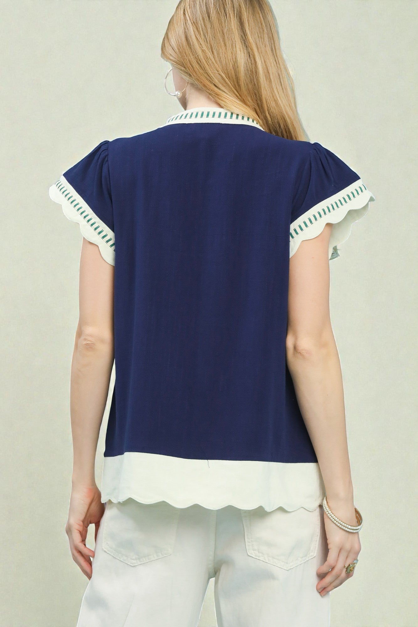 Navy blue top with white trim worn by a person on a plain background