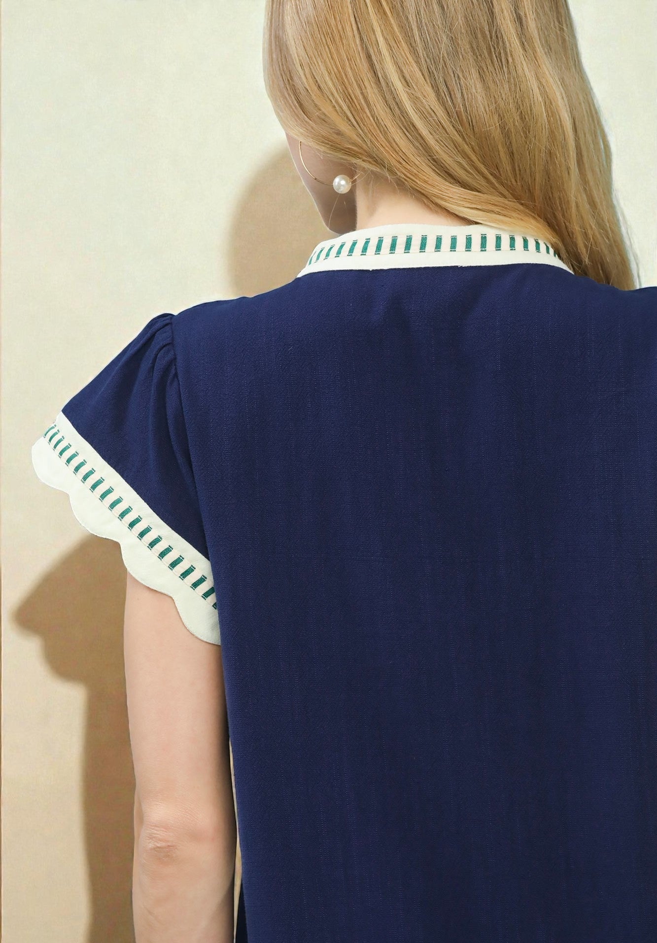 Navy blue dress with green and white trim on a plain background