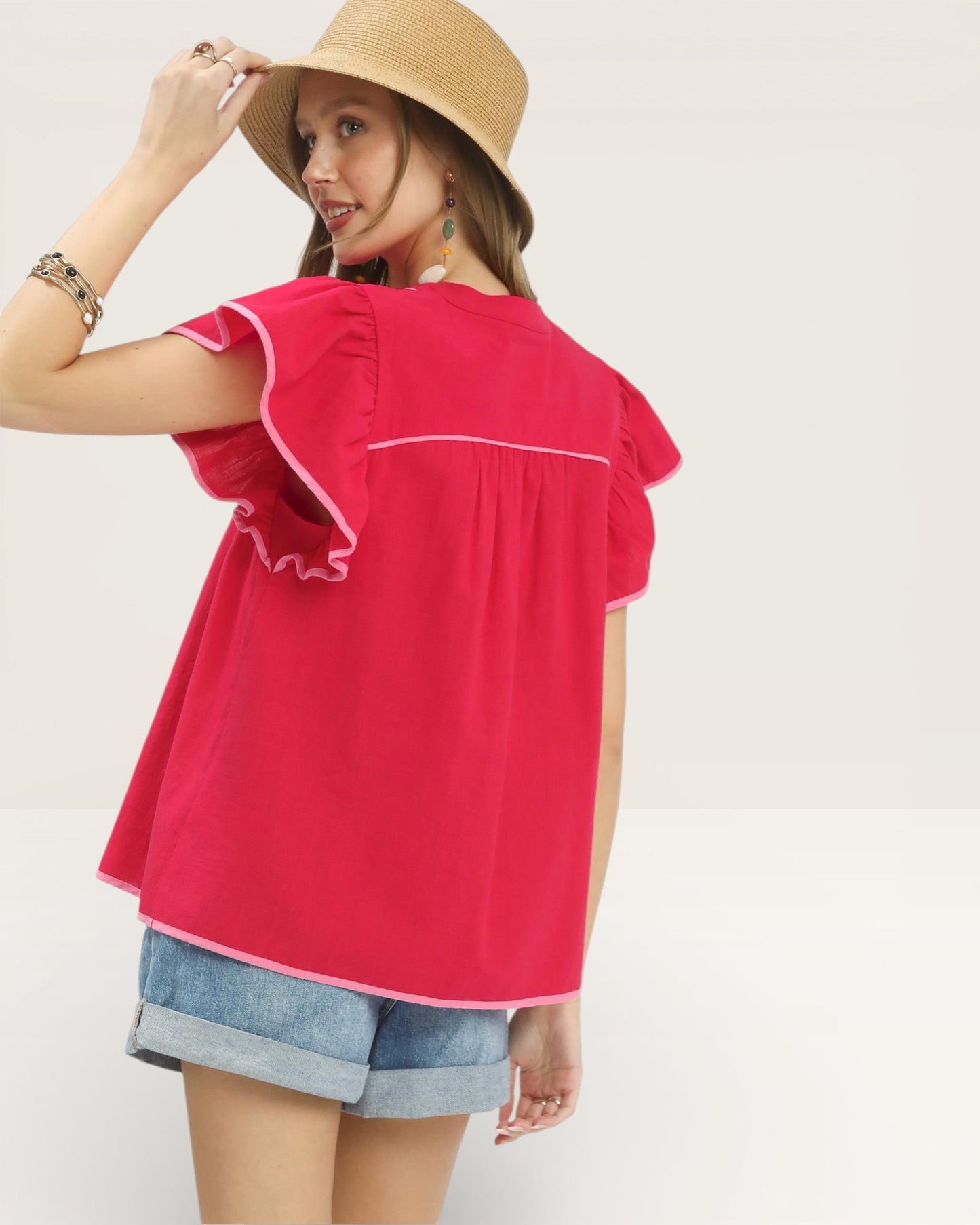 Woman wearing a red top and denim shorts with a white background