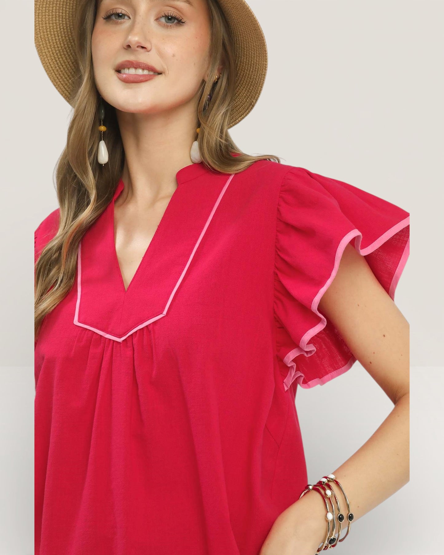 Woman wearing a pink blouse with white trim against a plain background