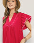 Woman wearing a pink blouse with white trim against a plain background