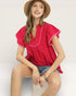 Woman wearing a red blouse and straw hat on a light gray background