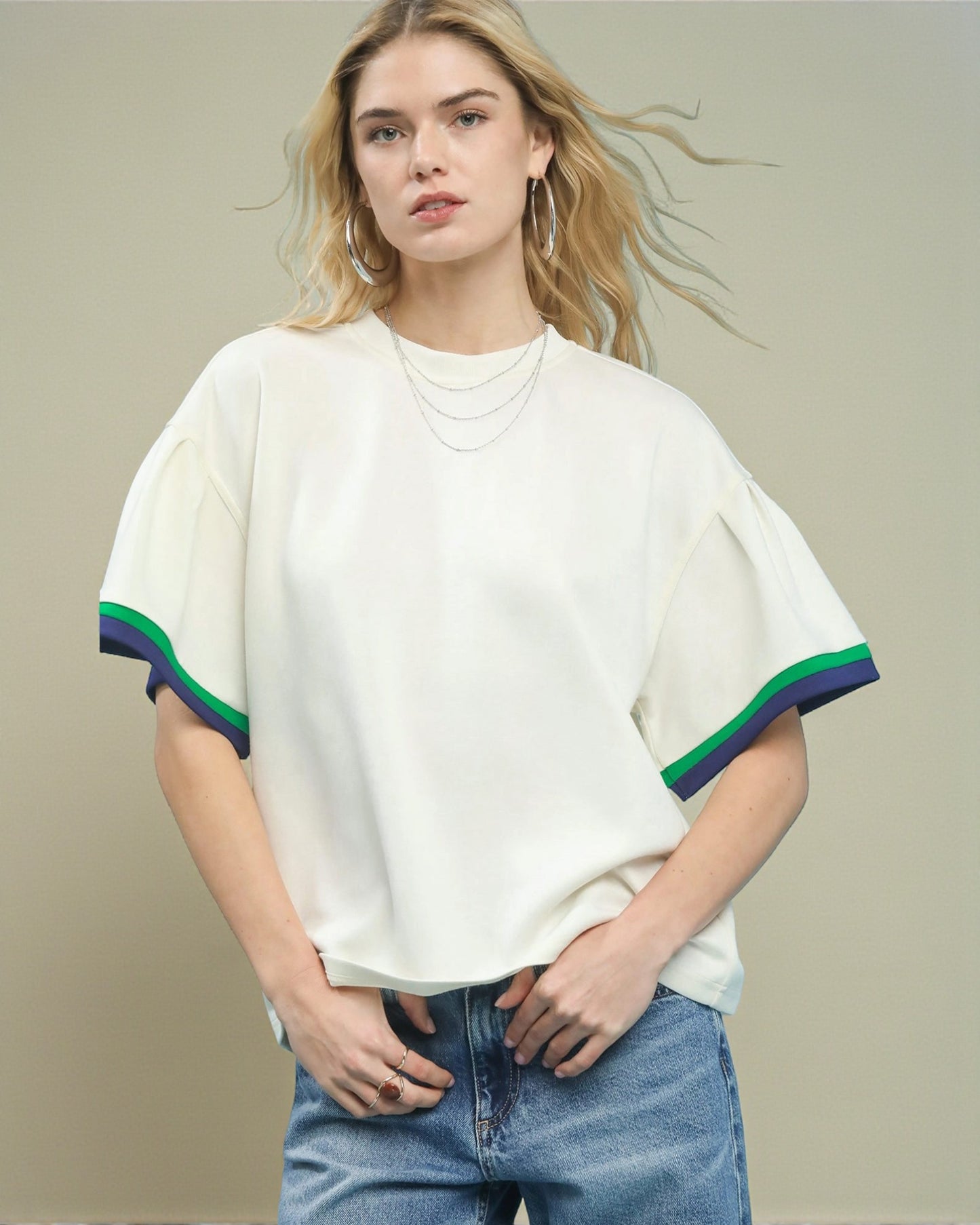 Woman wearing a white t-shirt with colorful trim against a beige background