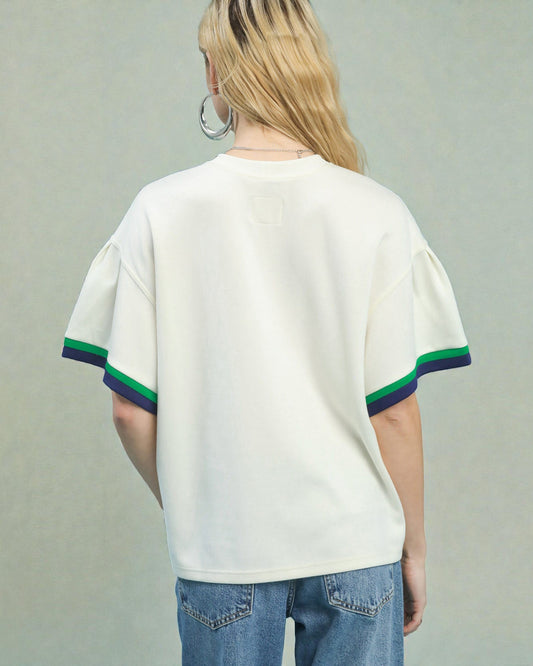 Person wearing a white t-shirt with green and purple trim on a plain background