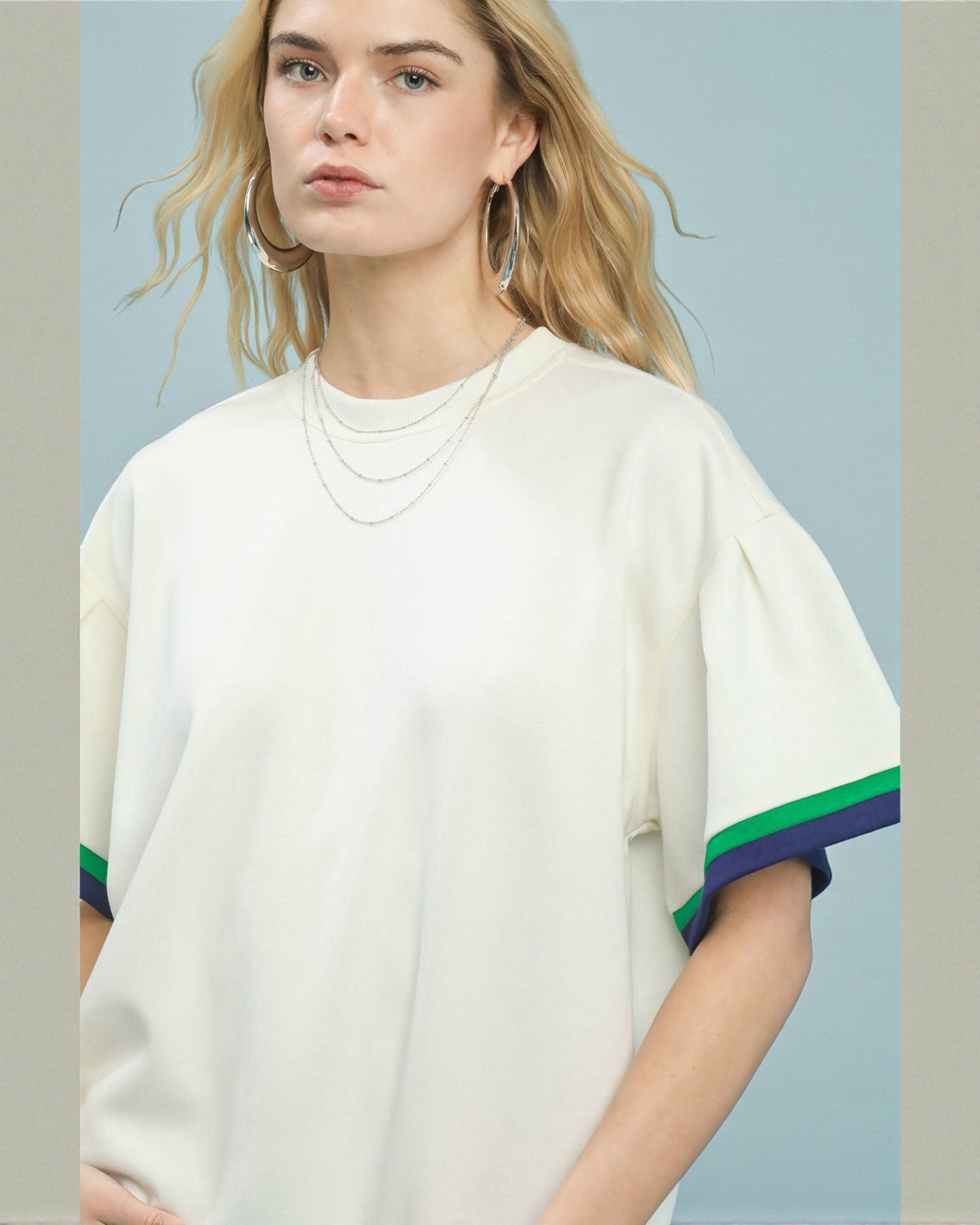 Woman wearing a white sweater with colorful sleeves against a light blue background