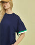 Woman wearing a navy blue top with green trim on a beige background