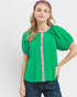 Woman wearing a green blouse with pink accents on a white background