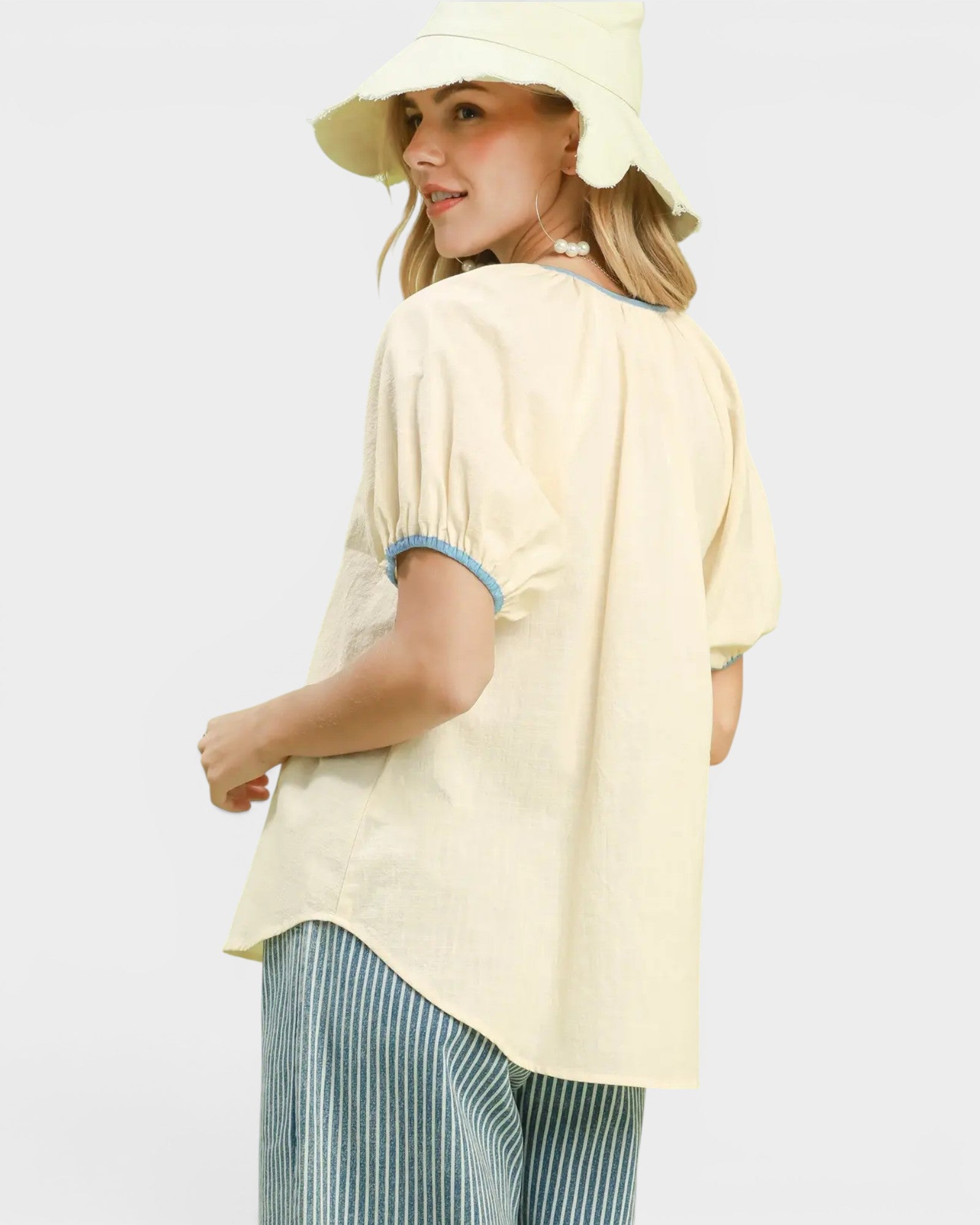 Woman wearing a light yellow blouse and hat on a white background