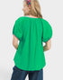 Green blouse with pink trim worn by a person on a white background