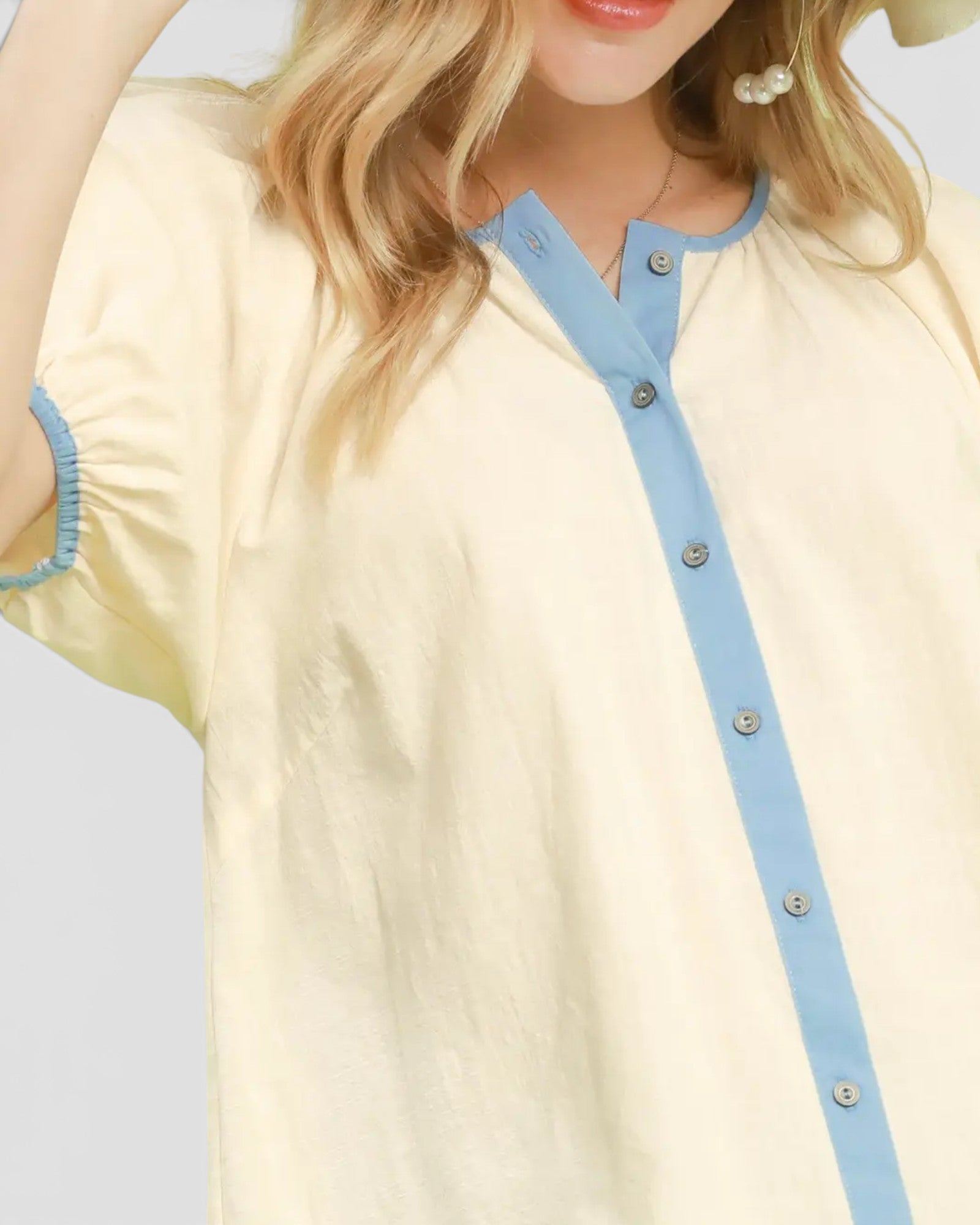 Light yellow top with blue accents worn by a person on a light gray background