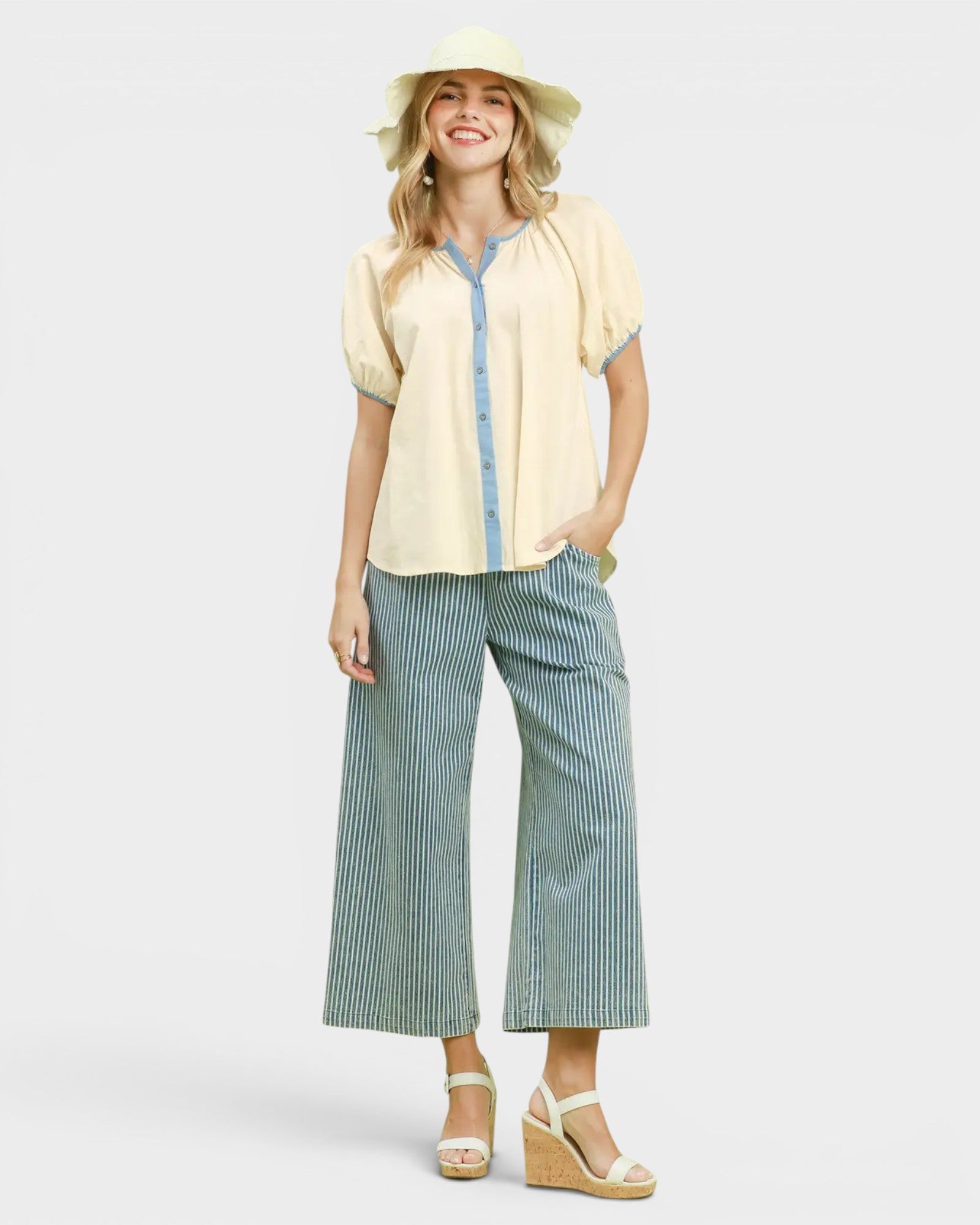 Woman wearing a yellow blouse with denim accents and green striped pants on a white background