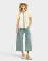 Woman wearing a yellow blouse with denim accents and green striped pants on a white background