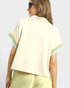 Woman wearing a light-colored blouse with colorful trim on a plain background