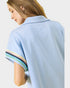 Light blue shirt with colorful trim on sleeves worn by a person, on a white background