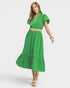 Woman wearing a green dress with a beige belt on a white background