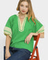 Woman wearing a green and beige top sitting on a red chair against a white background