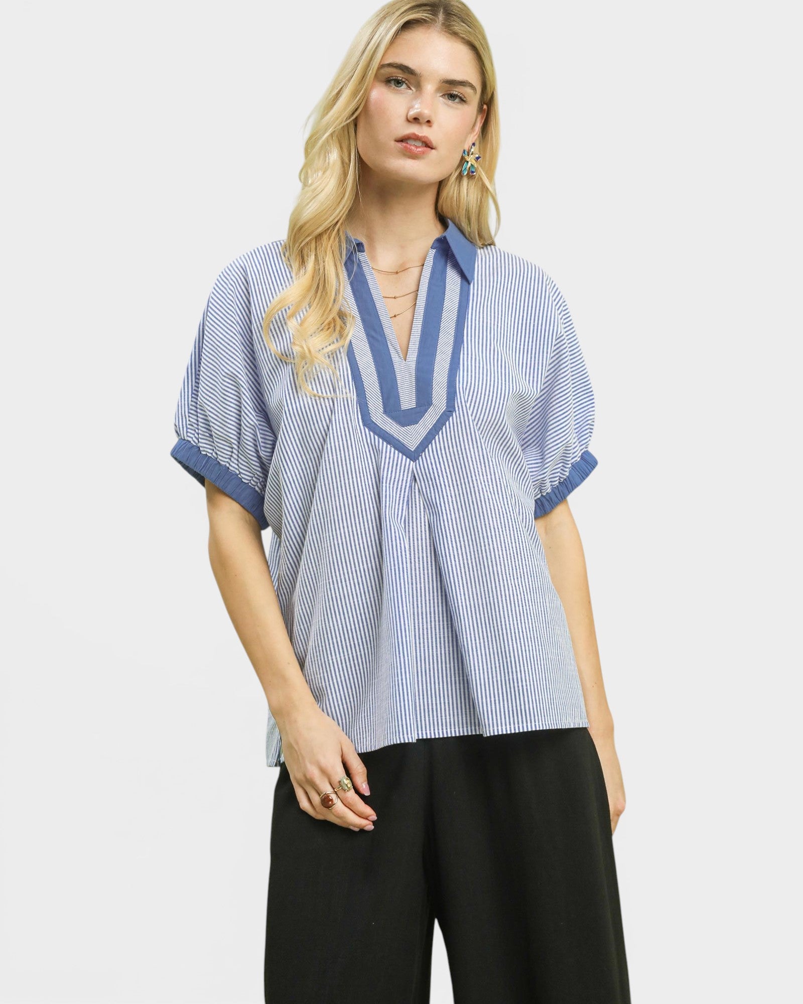 Woman wearing a blue and white striped shirt with black pants on a white background