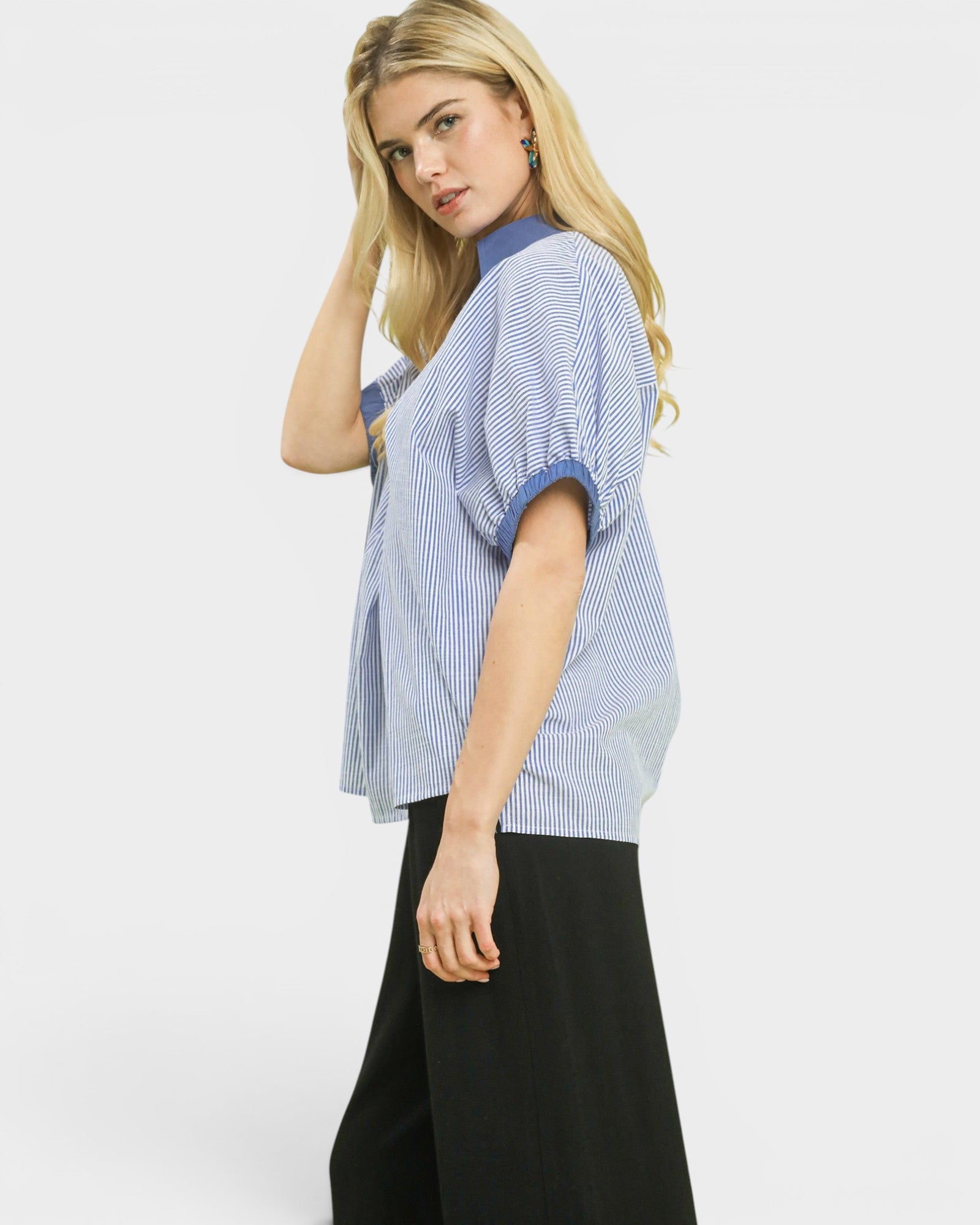 Woman wearing a blue and white striped shirt with black pants on a white background