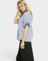 Woman wearing a blue and white striped shirt with black pants on a white background