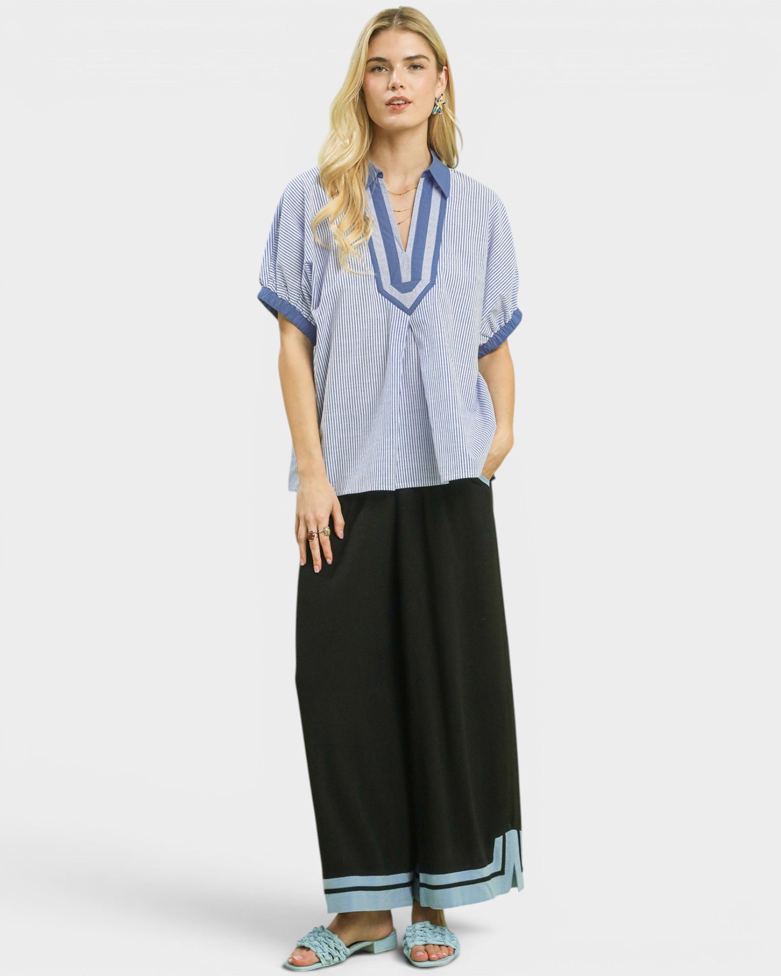 Woman wearing a blue and white striped shirt with black pants on a white background