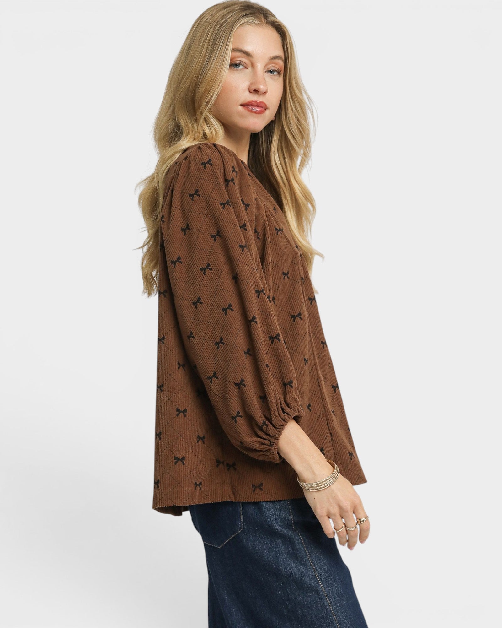 Woman wearing a brown blouse with black patterns on a white background