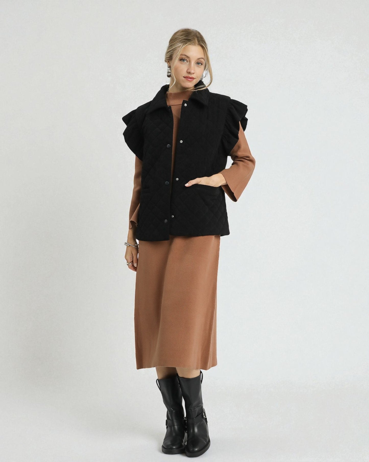 Woman wearing a black vest with brown sleeves and a long brown skirt on a white background