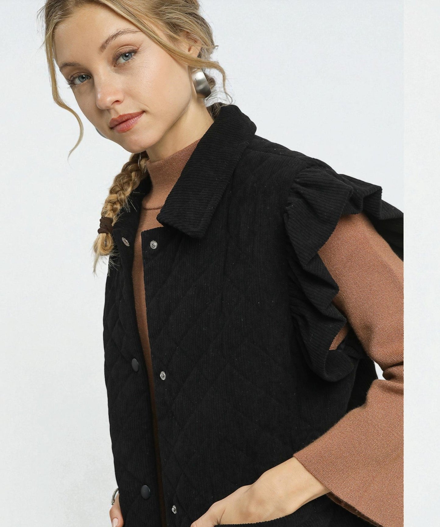 Woman wearing a black coat with ruffled shoulders on a white background