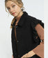 Woman wearing a black coat with ruffled shoulders on a white background