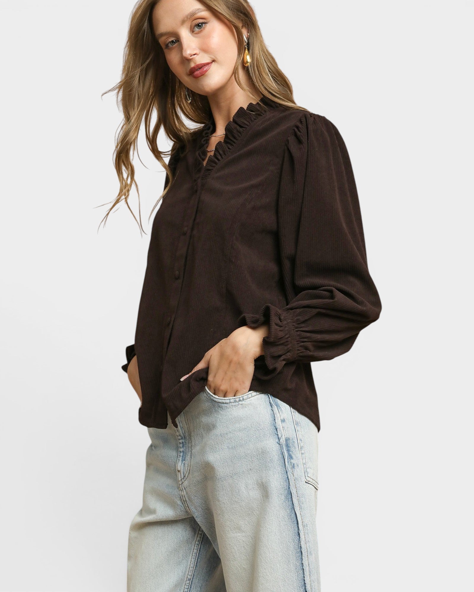 Woman wearing a brown blouse and light blue jeans on a white background
