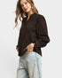 Woman wearing a brown blouse and light blue jeans on a white background