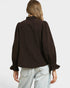 Person wearing a brown blouse with puffed sleeves on a plain background